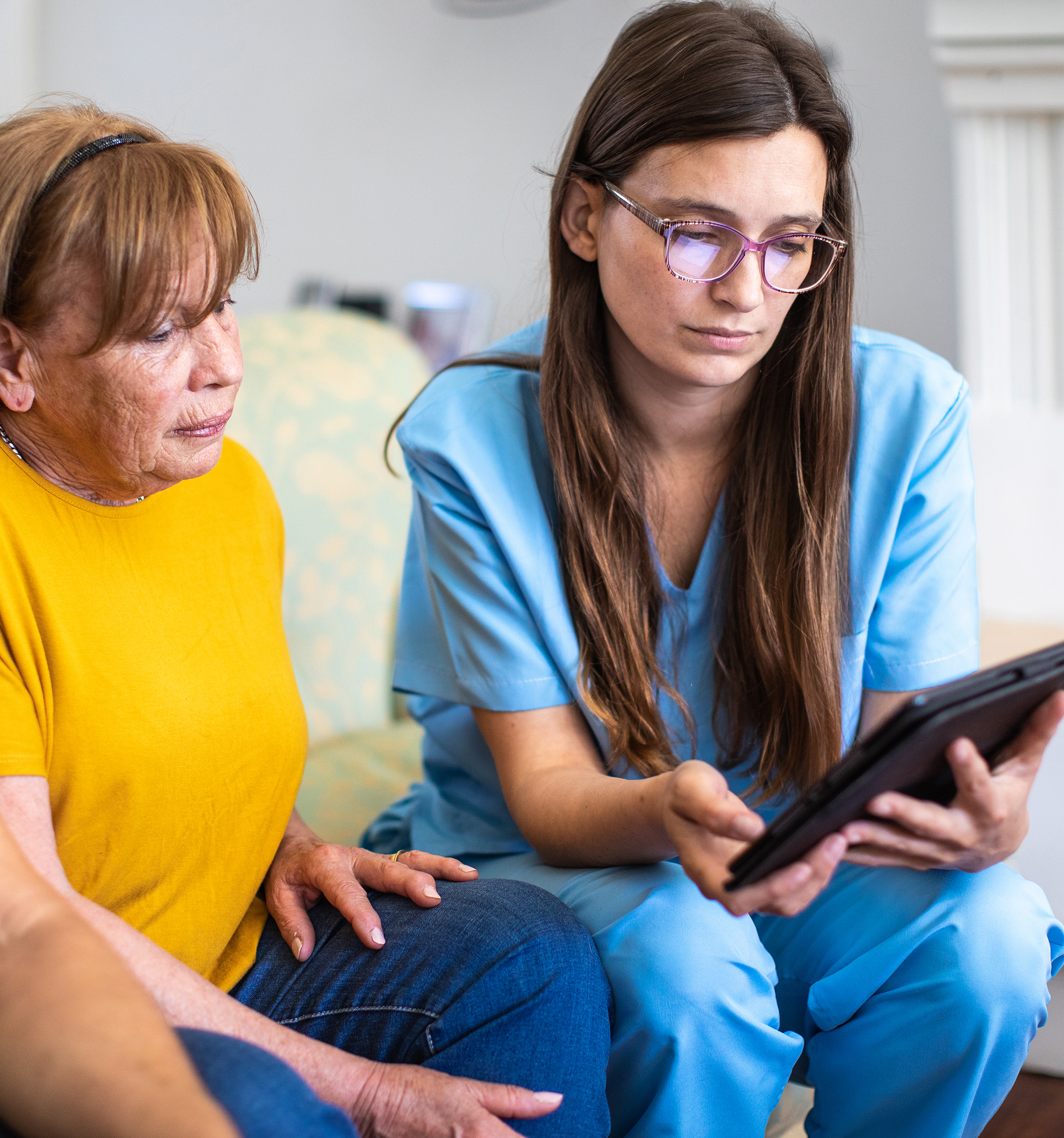 Female aged care worker talking with senior patients and using digital tablet